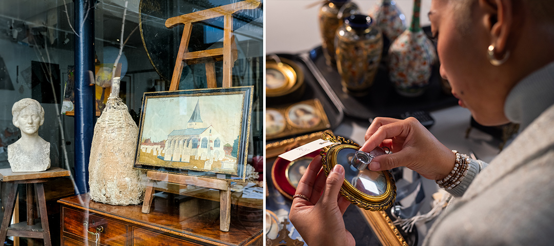 This split image showcases aspects of the antiques and art market. On the left, the interior of what appears to be an antique shop or gallery displays several items: a marble or stone bust of a woman on a stand, an aged bottle or vessel with a weathered appearance, and a framed painting of a church or chapel with a distinctive steeple, all arranged on wooden furniture. On the right, a person (partially visible from the side) wearing a light-colored outfit and jewelry is examining a small framed object, possibly a miniature portrait or medallion, using a magnifying glass or loupe. Decorative vases or urns can be seen in the background. The images together represent the world of art dealing, authentication, and collection – illustrating both the objects that might be affected by import regulations and the careful examination process that dealers and collectors undertake.