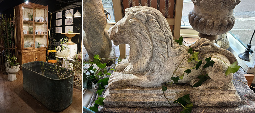 This image pair showcases architectural salvage and vintage garden elements: Left: A rustic interior space featuring a large weathered metal bathtub or trough in the foreground with a greenish-gray patina. Behind it stands a tall wooden display cabinet with glass doors containing various small items. The space has a warm, vintage aesthetic with wooden shelving and plant elements scattered throughout, suggesting a shop specializing in reclaimed or antique home and garden items. Right: A close-up of an aged stone garden sculpture depicting what appears to be a stylized horse or mythological creature in profile. The weathered stone has a textured, time-worn appearance with delicate ivy or small vines growing around it. The sculpture sits on a stone base near a window, with a decorative stone urn partially visible at the top. The patina and organic integration of plants gives it a romantic, timeless quality typical of European garden ornaments.