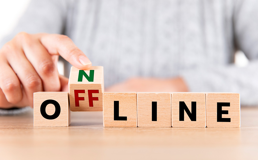 Hand placing a wooden block to change the word “offline” to “online,” symbolizing the antiques industry’s transition from paper records to digital visibility.