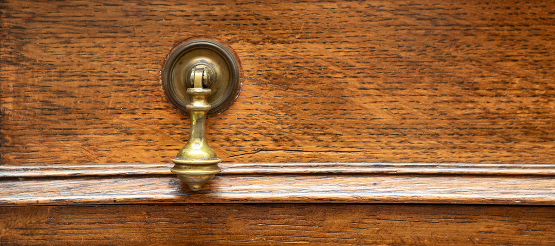 Close-up detail of an antique wooden drawer with original brass pull, highlighting the craftsmanship, patina, and durability of vintage furniture built to last generations.