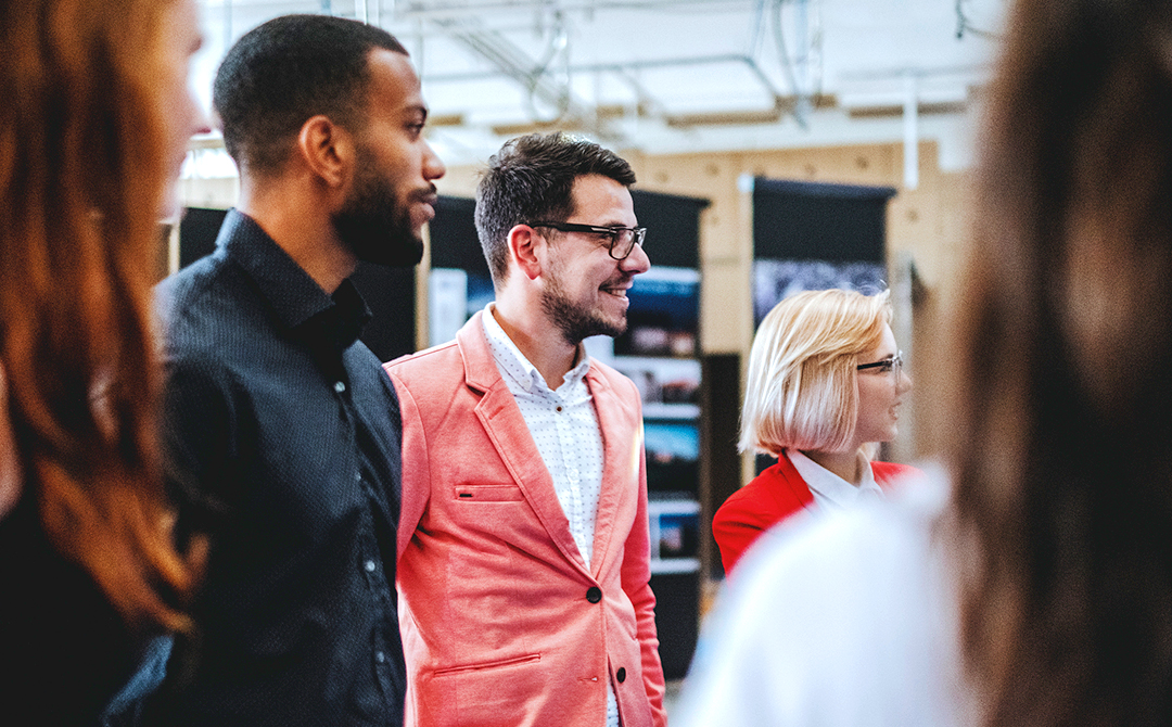 Designers and dealers speaking inside a trade fair booth during a US antiques event.