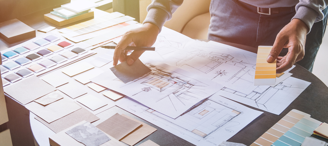 Designer reviewing floor plans, material samples, and finish swatches, reflecting the preparation and structured vision required before sourcing fast-moving vintage or auction pieces.