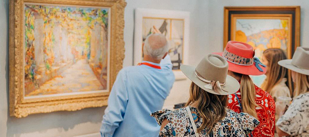Collectors and dealers examining framed artwork at an antiques and vintage market.