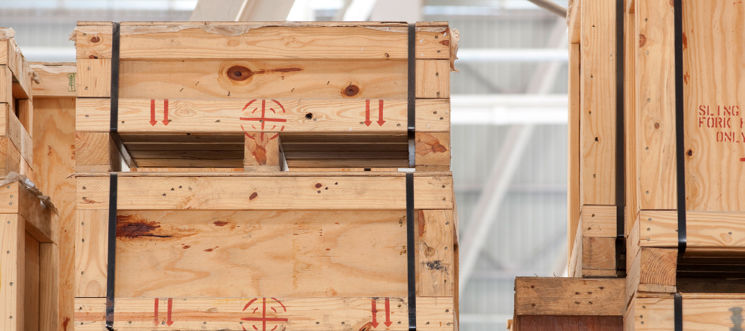 Stacked wooden shipping crates in a warehouse, symbolizing the logistics and coordination involved after successfully acquiring a one-of-a-kind antique at auction.