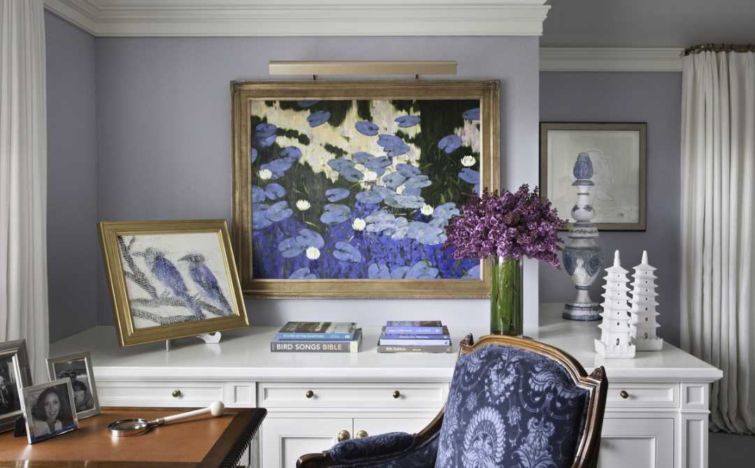 Interior by Alexa Hampton of Mark Hampton LLC featuring a layered vignette of framed artwork, antiques, and decorative objects arranged on a built-in cabinet, illustrating how art and historic pieces shape contemporary interiors.