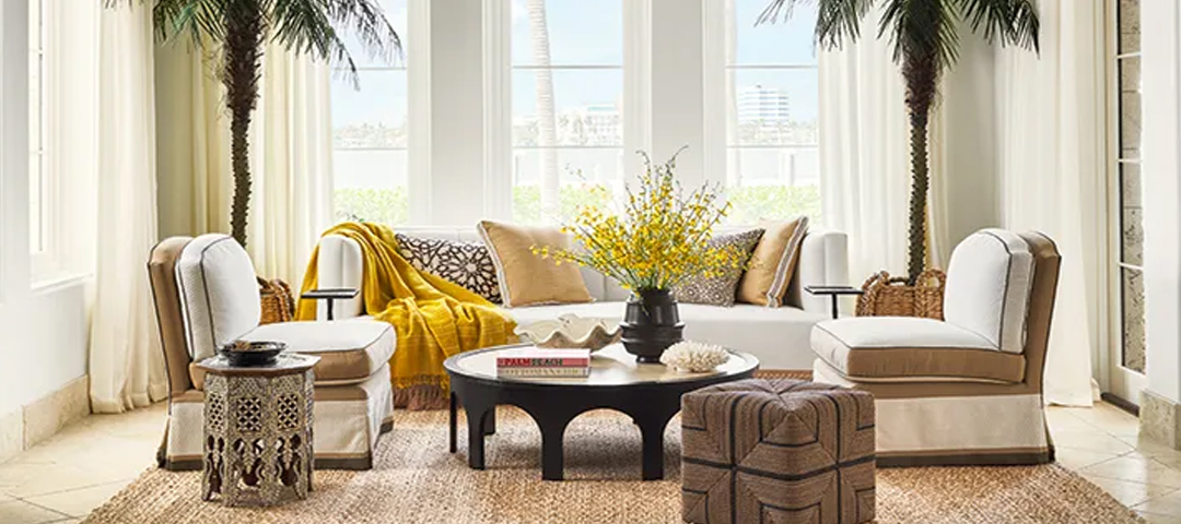 A light-filled sitting area with neutral upholstery, a carved wood table, and decorative accents that blend natural textures with vintage-inspired elements.