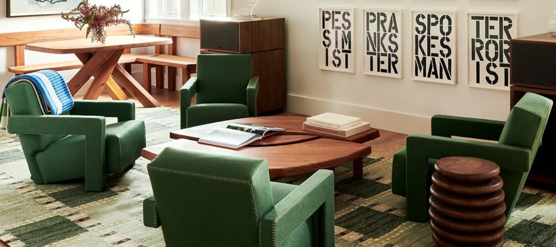 A modern interior with sculptural green chairs and a wood dining table, where bold contemporary forms are balanced by warm, natural materials and vintage influence.