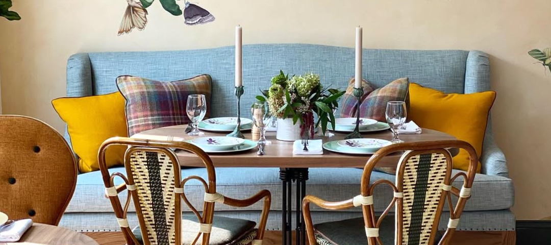 A cozy dining nook with bentwood chairs, patterned textiles, and layered table settings, combining vintage seating with contemporary upholstery and color.