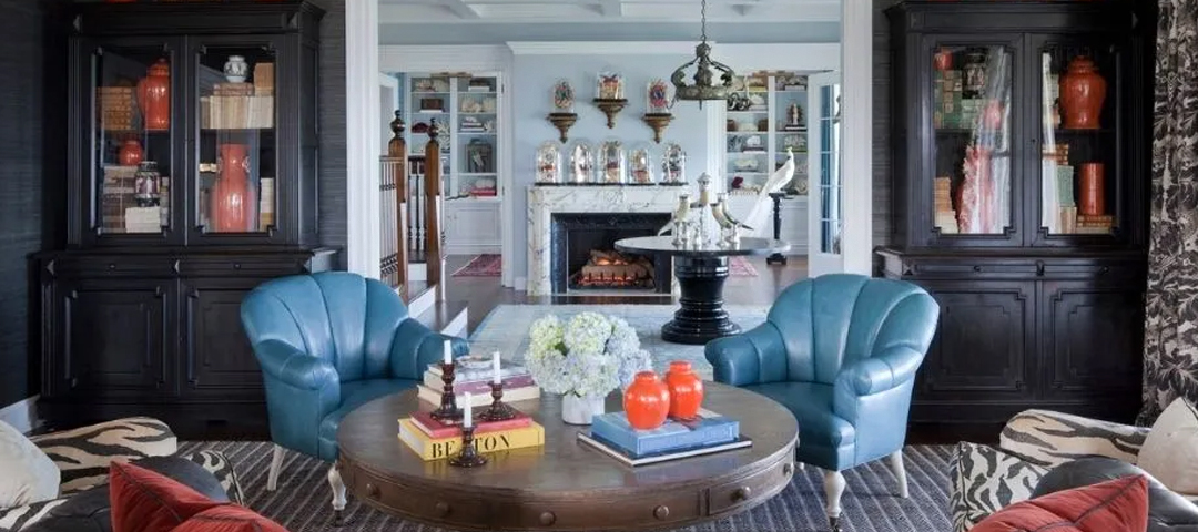 A classic living room with built-in cabinetry, upholstered armchairs, and collected decorative objects, illustrating a composed interior shaped by traditional pieces and personal detail.