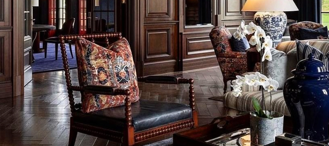 A richly detailed sitting area with wood-paneled walls, antique furniture, and patterned textiles, highlighting the role of historic pieces in creating a sense of permanence and warmth.