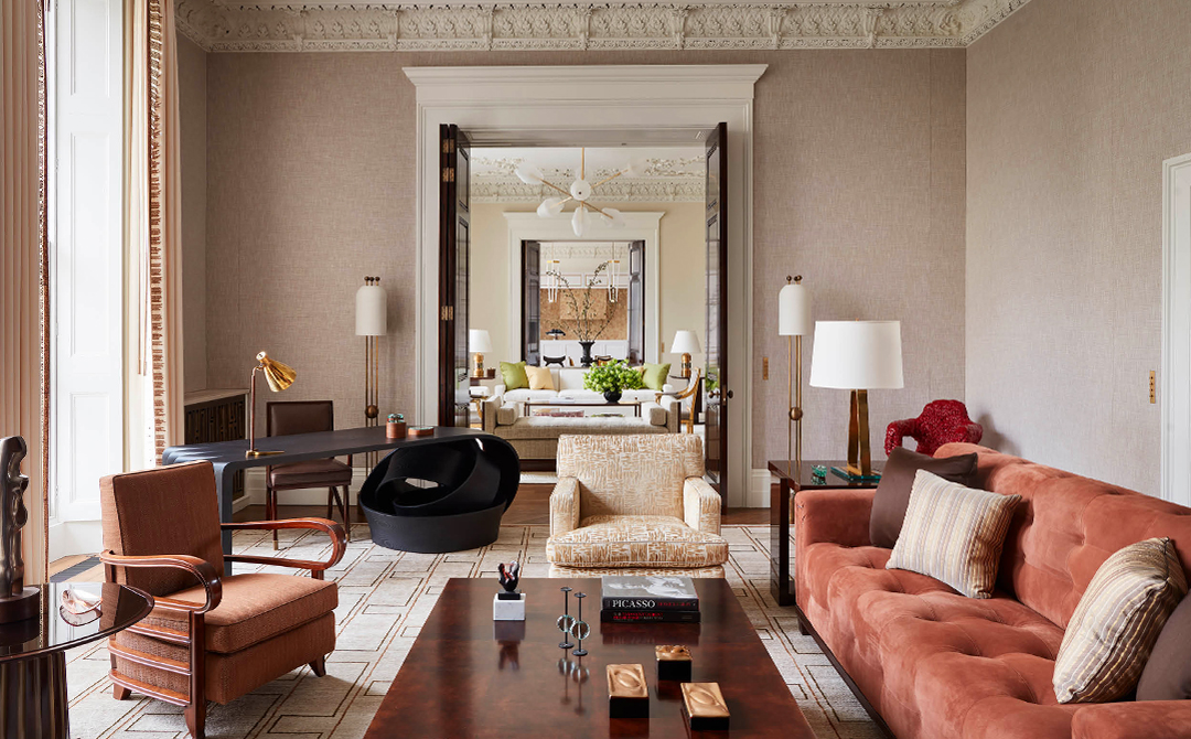 A David Kleinberg-designed living room layered with warm neutrals, sculptural seating, dark wood, and vintage-inspired furnishings that reflect the return of understated 1990s minimalism in contemporary interiors.