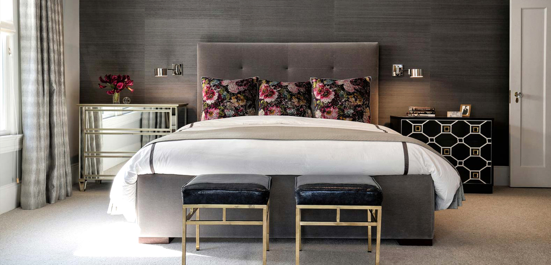 A tailored bedroom by Fisher Weisman Brugioni featuring charcoal grasscloth walls, polished metal accents, and layered textures that reflect the understated luxury and refined minimalism associated with 1990s-inspired interiors.
