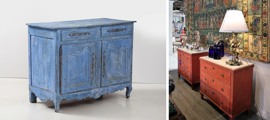 Weathered blue painted cabinet shown alongside richly colored antique chests in a contemporary showroom setting — reflecting the growing preference for interiors that feel personal, collected, and shaped over time rather than algorithmically perfected.