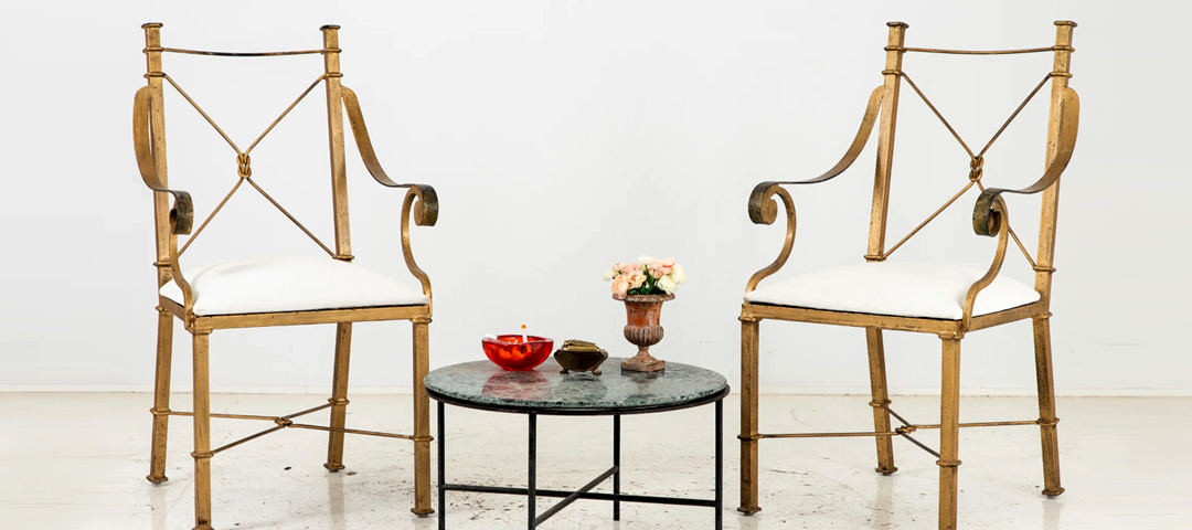 Pair of gilt metal armchairs arranged around a contemporary table — demonstrating the modern movement toward mixing periods, materials, and historical references to create interiors with greater depth and personality.