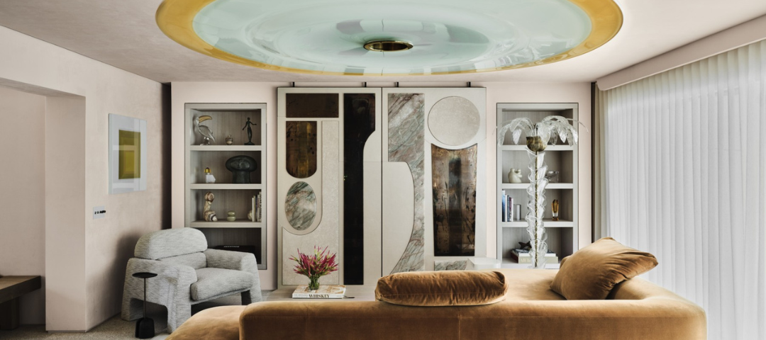 Living room with a circular glass ceiling fixture, built-in cabinetry faced in stone and lacquer panels, and a tan velvet sofa. Created by Citizen Artist. 