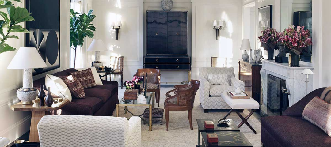 A David Kleinberg living room where two curved-arm caned French armchairs bring movement to a tailored contemporary scheme of white paneling and dark lacquer.