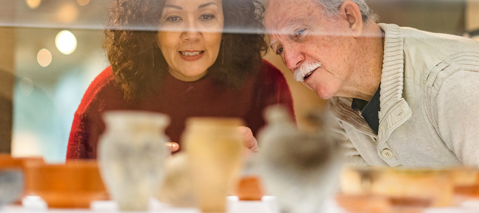 Dealer and collector examining antique vases together in a display case.