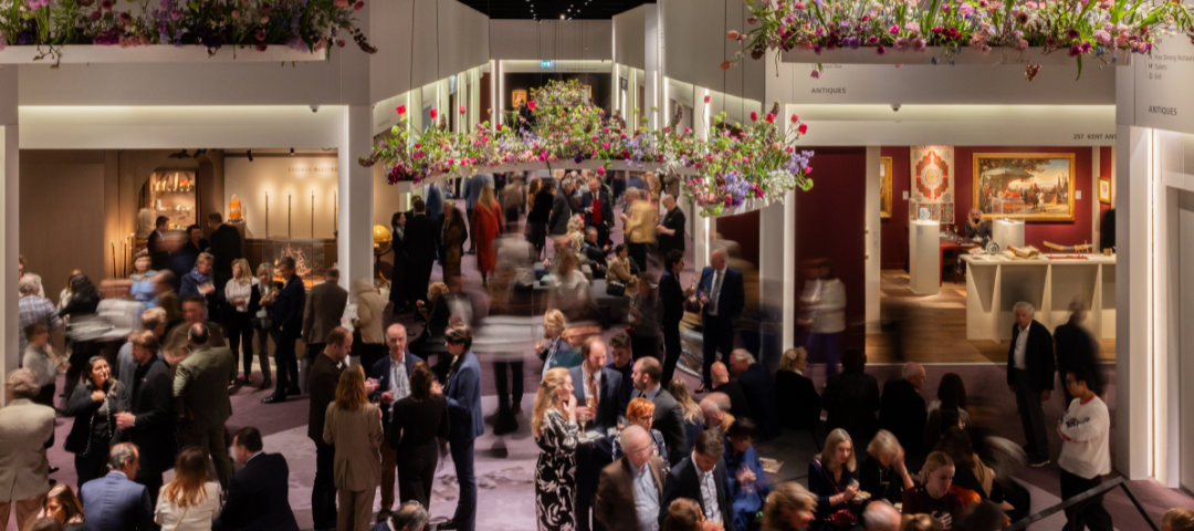 Crowded antiques and art fair with hanging floral displays, illustrating the community and connections built at trade events