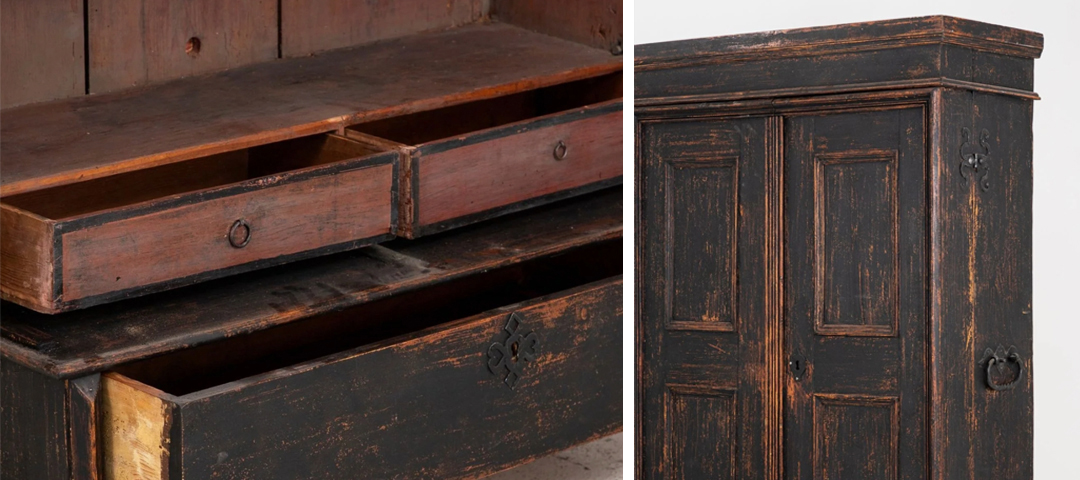 Detail of open drawers on a worn wood cabinet, alongside a black painted cupboard with carved iron hardware.
