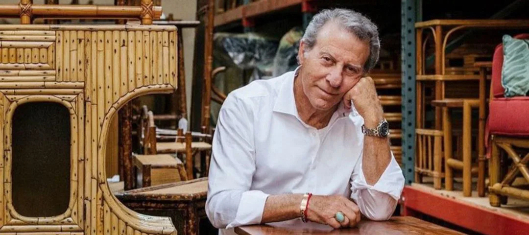 Harvey Schwartz of Harvey's on Beverly rests his chin on his hand in his warehouse, surrounded by vintage bamboo and rattan furniture