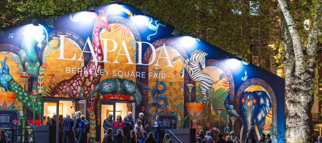 Evening visitors outside the LAPADA Berkeley Square Fair pavilion in Mayfair, its facade painted with giraffes, zebras, peacocks, and elephants